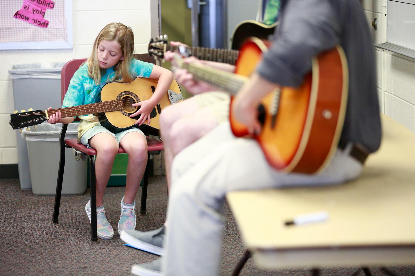 student teaching child how to play guitar
